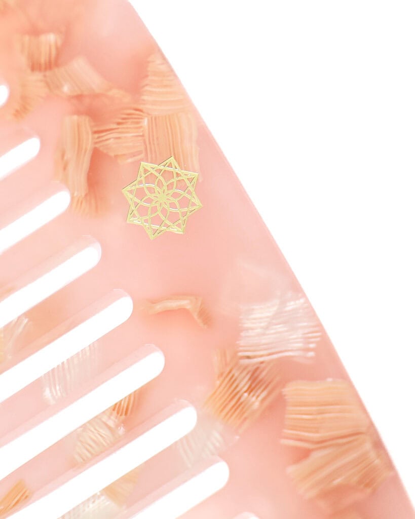 Detaillierte goldene Haarklammer auf rosafarbenem Haarstyling-Accessoire, elegant und modisch.