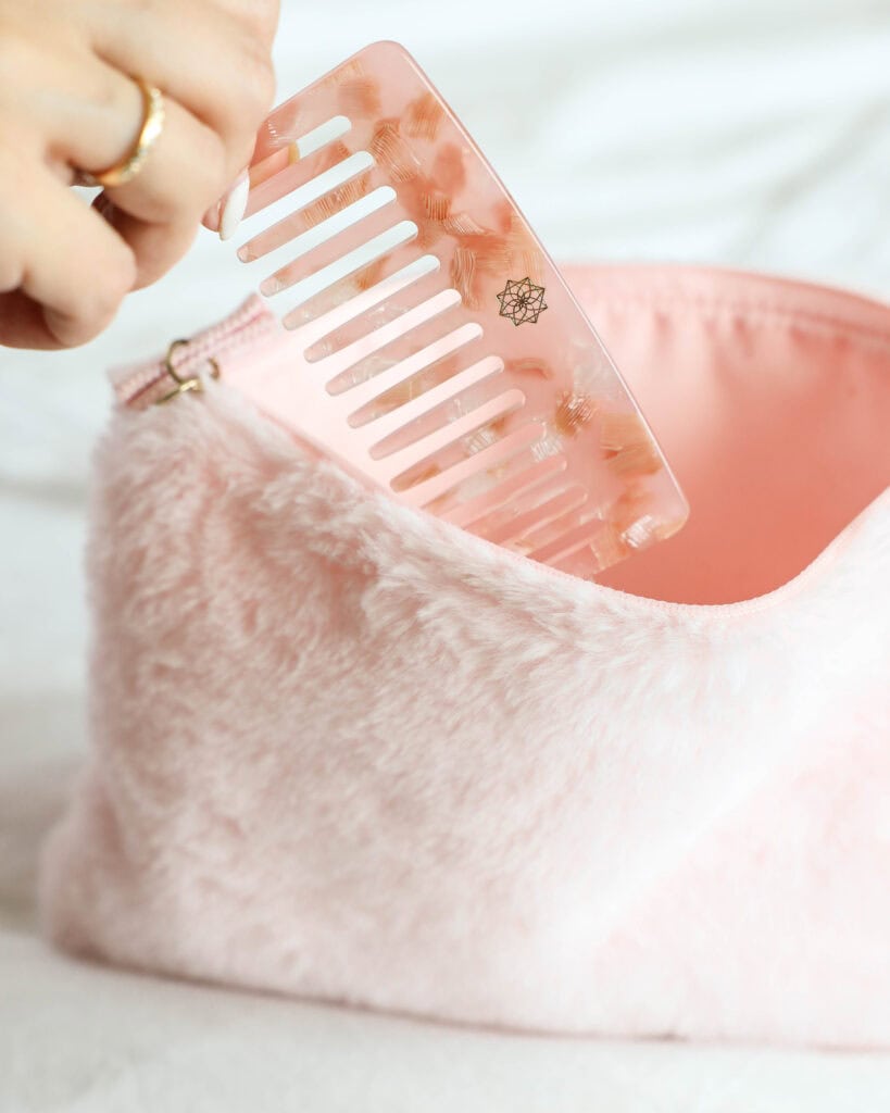 Helle pinke Haarbürste in einem kuscheligen Beutel aufbewahrt, stilvoll und praktisch für unterwegs.